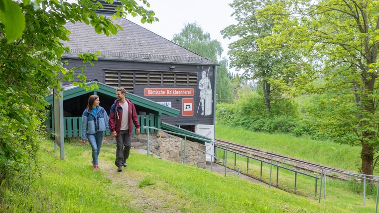 Two people walking in front of the Roman lime kiln in Iversheim.