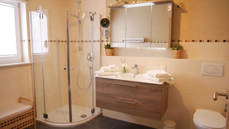 Een moderne badkamer met douche en houtontwerp. Er zijn grote spiegels en een heldere, uitnodigende stijl.