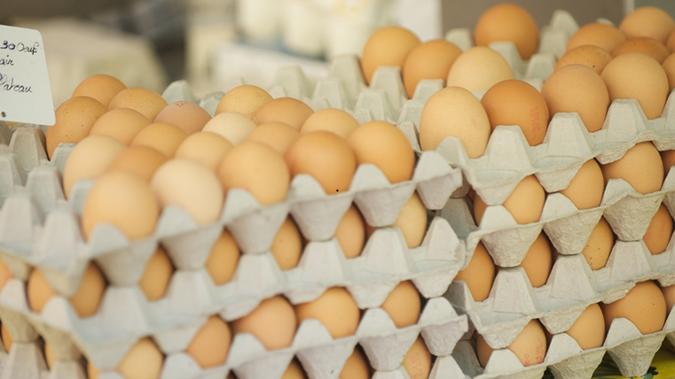 Meerdere gevulde eierpallets zijn op elkaar gestapeld en staan te koop.