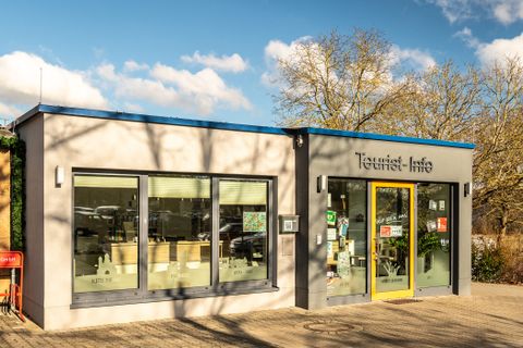 Tourist-Info, im Hintergrund sieht man blauen Himmel und ein paar Bäume.