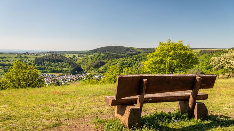 Houten bank met uitzicht op het groene landschap en het dorp in de verte.