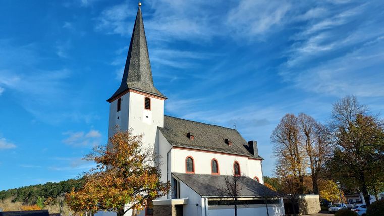 Martinuskerk in Nettersheim met blauwe lucht en herfstbomen.
