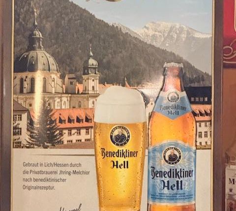 An advertisement for Benediktiner Hell Beer. The image shows a beer glass and a bottle in front of a picturesque mountain landscape.
