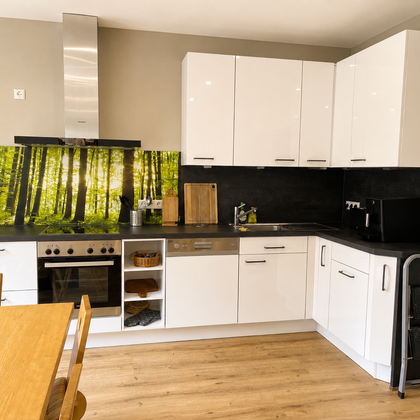 Een moderne keuken met witte kasten en een donkere werkruimte. Op de achtergrond is er een opvallende wandbekleding met een bosmotief.