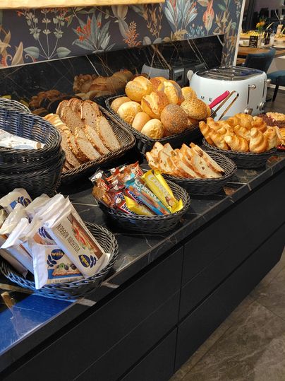 Une sélection de pain frais et de petits pains dans des paniers. Au premier plan, on peut également voir des snacks et des bonbons.