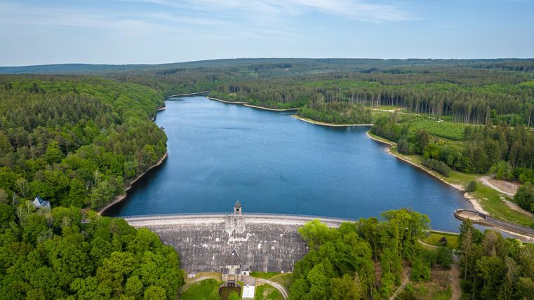A quiet reservoir surrounded by green forests. The landscape is idyllic and invites relaxation.