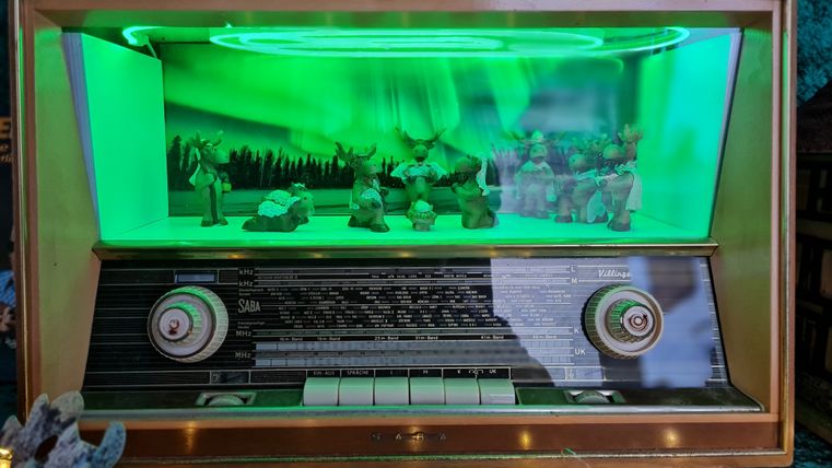 Altes Radio mit grün beleuchteter Szene von Rentieren im Inneren.