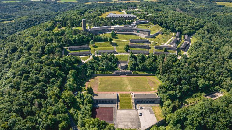 Aerial view of Vogelsang IP surrounded by green forests and hills.