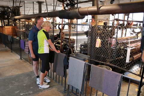 Twee mensen kijken naar machines in een historische textielfabriek.