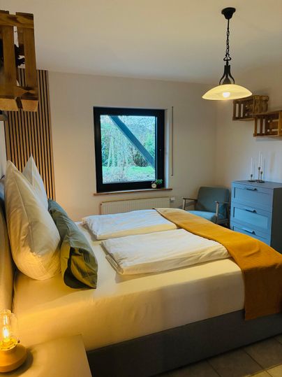 Een gezellige slaapkamer met een groot bed en moderne meubels. Het raam biedt uitzicht op de natuur en zorgt voor aangenaam licht.