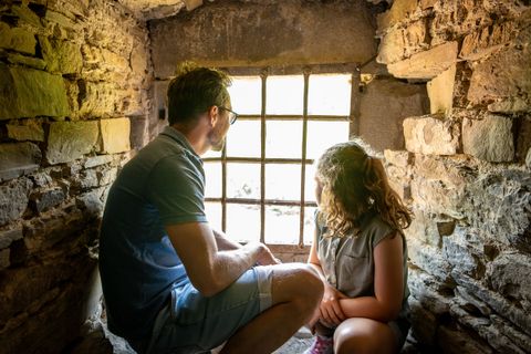 Vater und Tochter sitzen in einem Schloss auf einem Fenstersims
