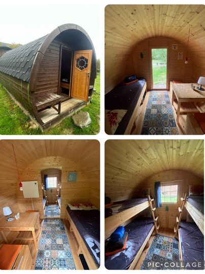 Une cabane en bois confortable avec une forme ronde et une porte de véranda en bois. À l'intérieur, il y a deux espaces de sommeil avec un revêtement de sol coloré et un mobilier simple.