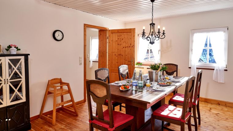 Ein einladender Essbereich mit einem großen Holztisch und roten Stühlen. Das Zimmer hat helle Wände und großes Fensterlicht.