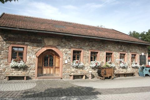 Ein eingeschossiges längliches Gebäude aus Bruchsteinen und mit einem rotem Ziegeldach. Der linksgelegene Eingang hat einen Rundbogen aus rötlichem Sandstein.Die Holztür ist im oberen Bereich aus Glas und mit einem Schmiedegitter verziert. Rechts und links sind 2 feststehene Holzelemente. Links des Einganges gibt es 1 Fenster, rechts davon fünf, vierreckige Sprossenfenster, die ebenfalls von Sandsteinen umrahmt sind. Vor den Fenstern sind Blumenkästen mit weißen und roten Blumen. Der Hof vor dem Gebäude ist gepflastert.
