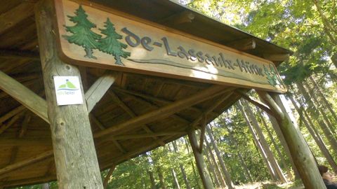 Inscription de la cabane de Lassaulx avec deux sapins verts sur une planche de bois. Appliqué à la cabane en bois