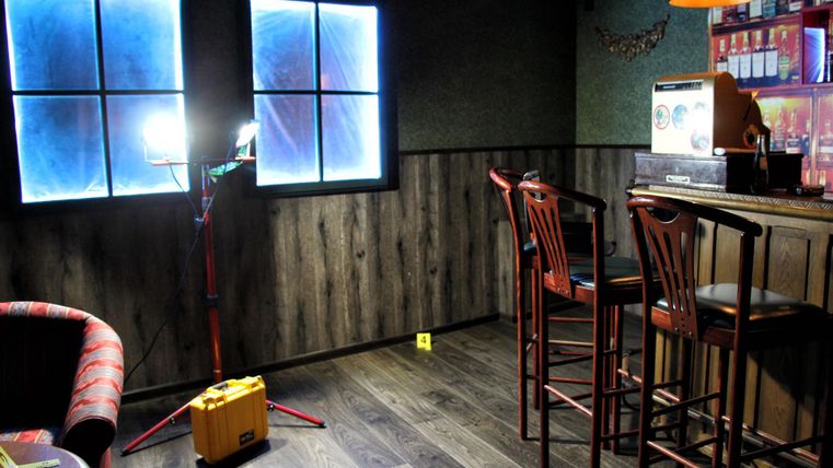 Room with wooden floor, bar with bar stools, two windows