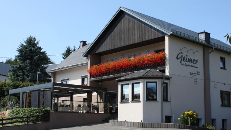 Een modern gebouw met bloeiende bloemen op het balkon. De omgeving is groen en uitnodigend.