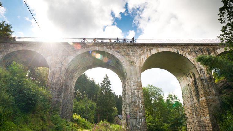 Cyclistes sur le viaduc de Reichenstein de la Vennbahn par temps ensoleillé.