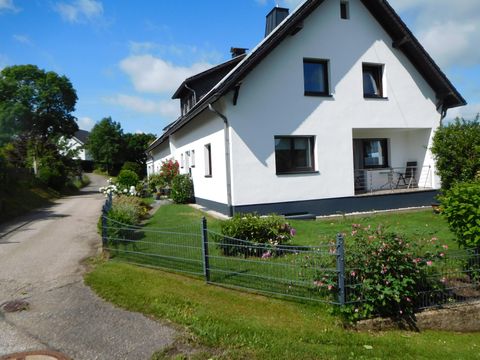 Ein schönes, modernes Haus mit einem gepflegten Garten. Es steht an einer ruhigen Straße, umgeben von grüner Landschaft.