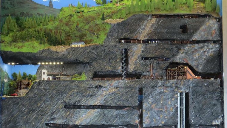 A model of a mining landscape with various layers and structures. The depiction shows trees, buildings, and mine entrances.