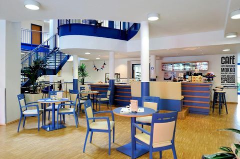 A modern café with blue and white elements. Tables and chairs invite you to linger, while in the background the counter is visible.