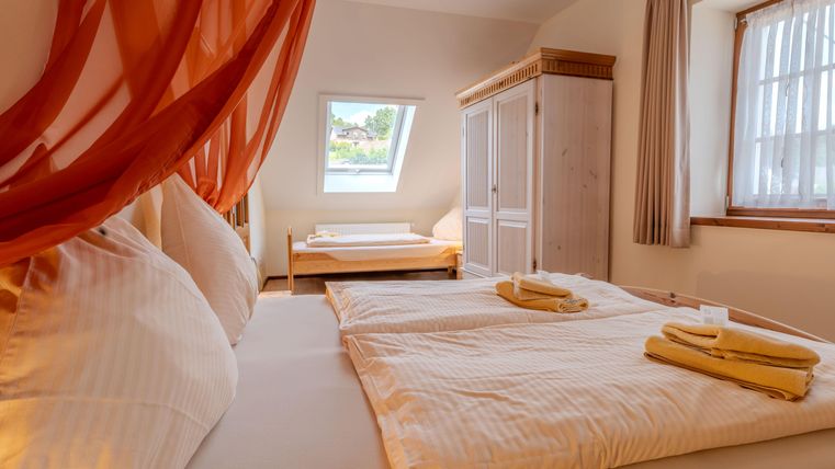 Vakantieappartement Veldmuis - Een gezellige slaapkamer met twee bedden en een raam dat natuurlijk licht binnenlaat. Zachte beddengoed en een mooie kast geven de ruimte een uitnodigende sfeer.