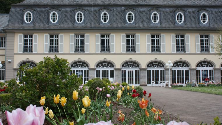 Een evenementenruimte met veel stoelen in rijen. De muren zijn verlicht met rood licht en een podium is op de achtergrond zichtbaar.