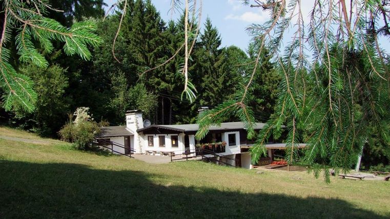 A quiet house in a green environment with trees in the background. The sunny atmosphere conveys a sense of relaxation and connection to nature.
