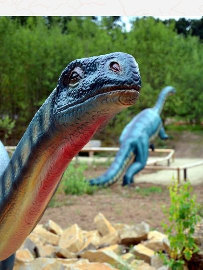 Dinosauriermodell im Dinopark mit grünem Hintergrund.