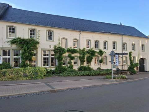 Un bâtiment charmant avec des murs blancs et des plantes vertes. Les fenêtres sont grandes et accueillantes, et l'environnement est soigné.