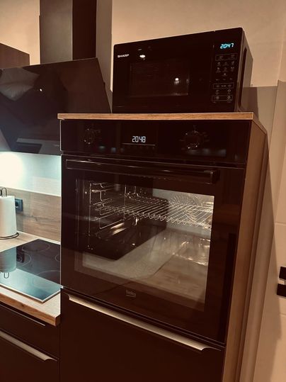 Une cuisine moderne avec un four à micro-ondes et un four intégré. Les deux appareils sont en noir élégant avec un affichage numérique.