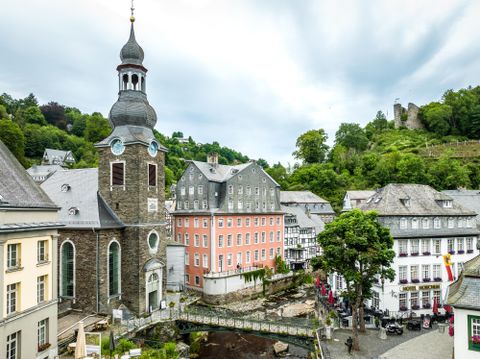View of the old town of Monschau with the striking Red House and a church in the foreground.