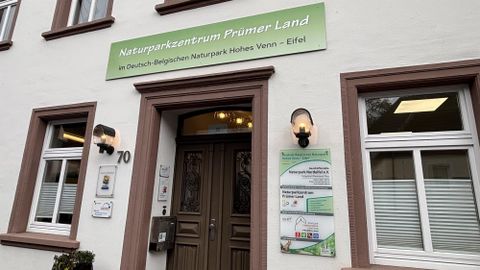Das Bild zeigt das Naturparkzentrum Prümer Land mit einem einladenden Eingangsbereich. Über der Tür befindet sich ein Schild mit dem Namen des Zentrums und Informationen zu den Naturparks in der Region.
