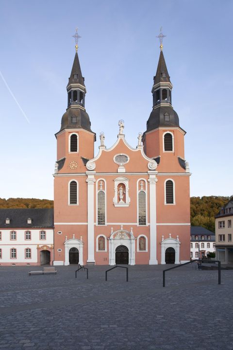 Eine beeindruckende Kirche mit zwei Türmen und einer rosa Fassade. Der Platz vor der Kirche ist weit und ruhig.