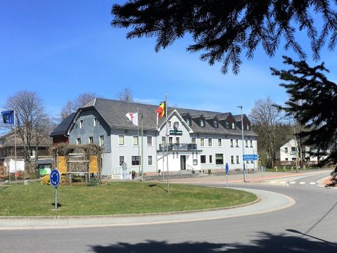 Ein modernes Gebäude an einer Straßenkreuzung mit Flaggen. Es ist ein klarer blauer Himmel zu sehen.