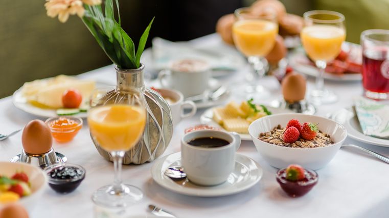 Een weelderige ontbijttafel met verschillende gerechten. Er zijn eieren, muesli, vers fruit en dranken.