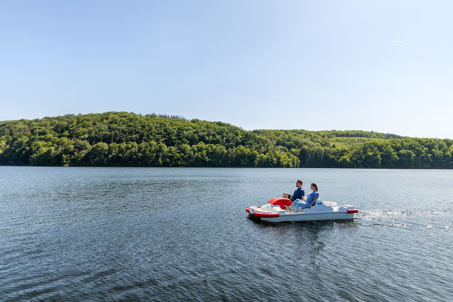 Zwei Personen fahren Tretboot auf dem Rursee