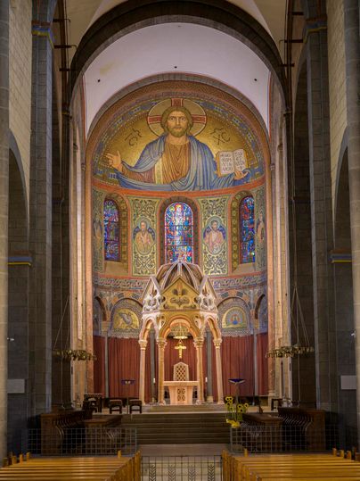 Une impressionnante intérieur d'église avec des vitraux colorés et une fresque religieuse. La zone de l'autel est magnifiquement conçue et dégage calme et majesté.