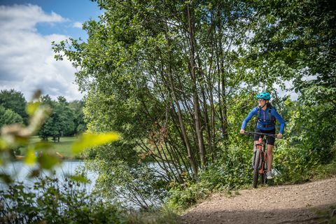 Eine Person unterwegs auf einer Mountainbike-Tour. Neben ihr ist der Freilinger See zusehen.