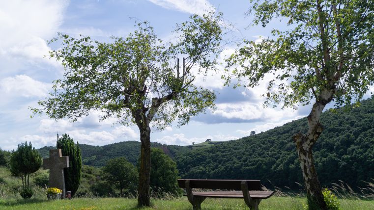 Rest area with bench, trees and cross in the Eifel.