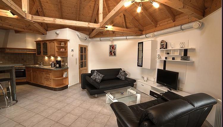 Moderne woning met houten plafond en een gezellige zithoek. De open keuken is uitgerust met houten kasten en moderne apparaten.