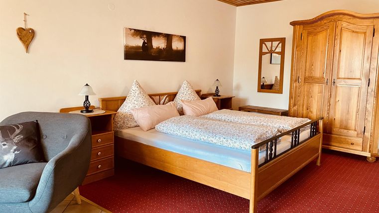 Een gezellige slaapkamer met een tweepersoonsbed en twee hoofdkussens. De kamer is vriendelijk ingericht en heeft een rustieke kledingkast.