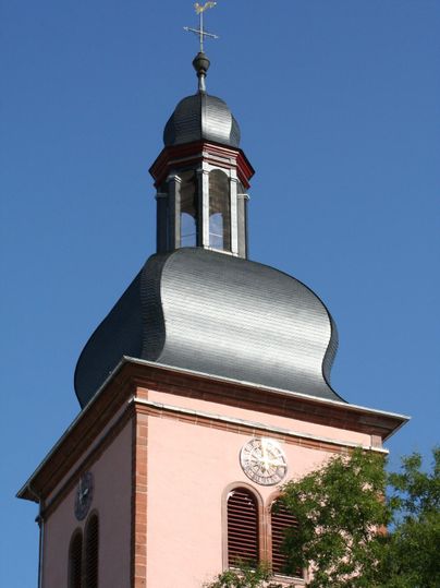 Een kerktoren met een markante, ronde koepel. De lucht is helder en blauw.
