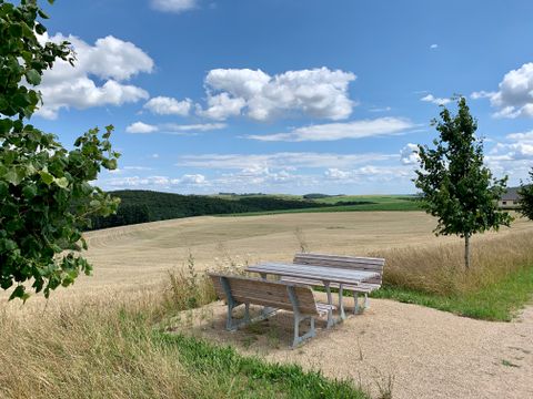 Eine Holzsitzgruppe mit Ausblick auf die trockenen Felder und die Waldstücke