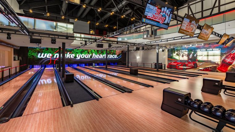 Une moderne piste de bowling avec plusieurs lanes et de grands écrans. L'établissement est lumineux et accueillant.
