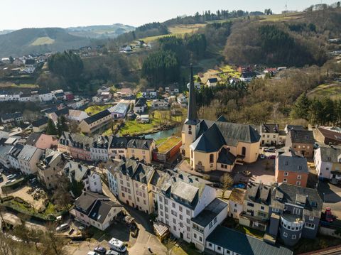 Eine malerische Stadt mit bunten Häusern und einer Kirche im Zentrum. Umgeben von sanften Hügeln und viel Natur.