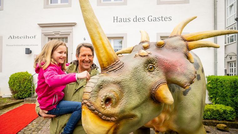 Ein Mann und ein Kind betrachten eine lebensgroße Dino-Nachbildung