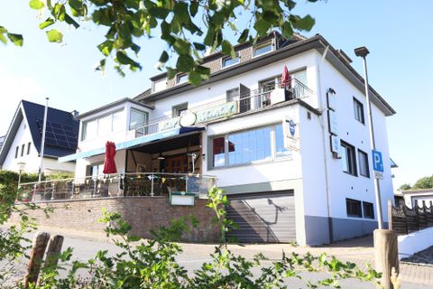 A modern building with a cozy outdoor area. The facade is bright and inviting, with a parking lot nearby.