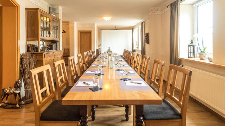 Een grote vergaderruimte met een lange houten tafel en veel stoelen. Op de tafel bevinden zich decoraties en notitiebladen voor de deelnemers.