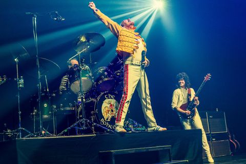 Ein Sänger in einem glitzernden Anzug steht auf der Bühne und singt. Neben ihm sitzt ein Pianist am Klavier und begleitet ihn.